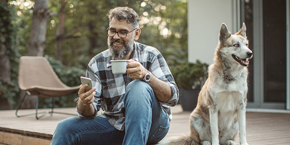 Middle Aged Man Drinking Coffee And Receiving A Health Insurance Alert Via Text