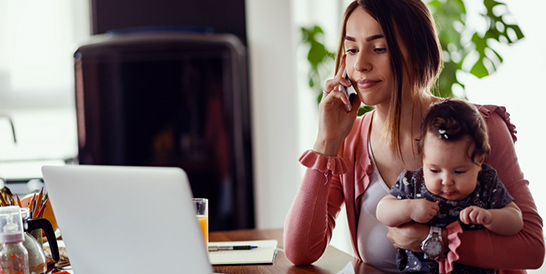 Mother Holding Infant While  On The Phone For An Individual Healthcare Plan