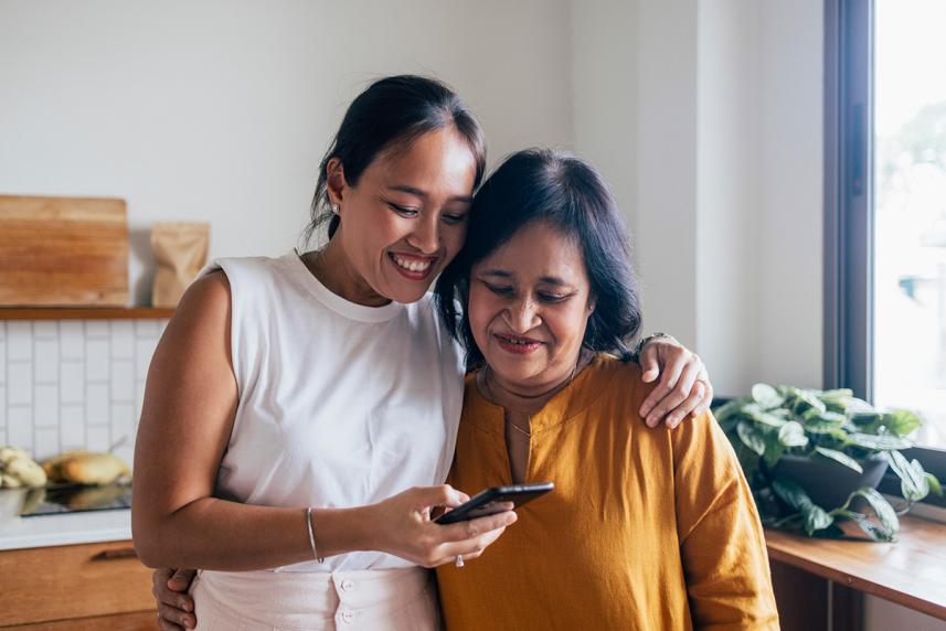 Mother and daughter hugging while looking at phone