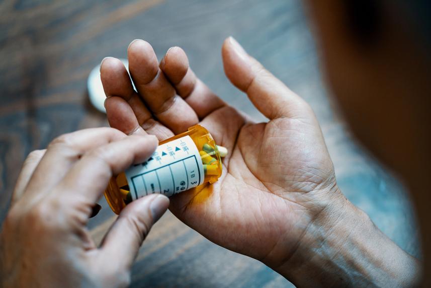 Pills from a pill bottle being dispensed onto a hand