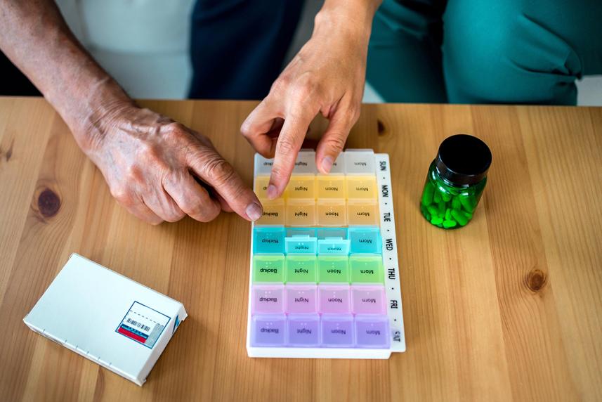 Two hands pointing at a pill organizer