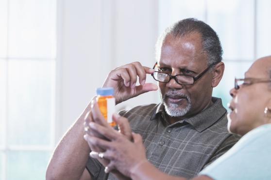 A couple holds up a prescription bottle and reads it together.