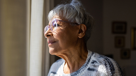 Older woman looking out a window.