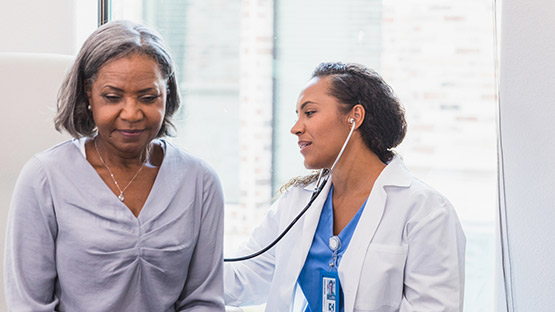 A doctor uses a stethoscope on a woman's back