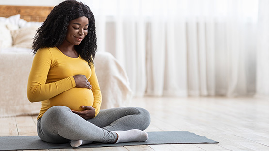 Pregnant woman is sitting on the floor.