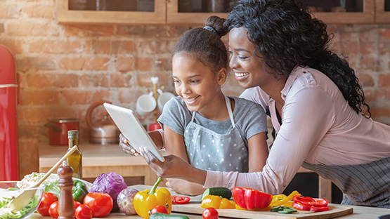 A mother and daughter look up a recipe on their tablet