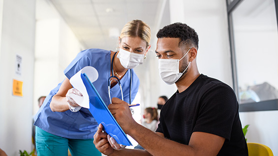 A man fills out forms in a hospital waiting area