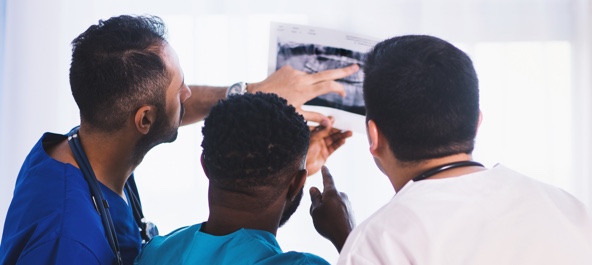 A trio of physicians examining an x-ray